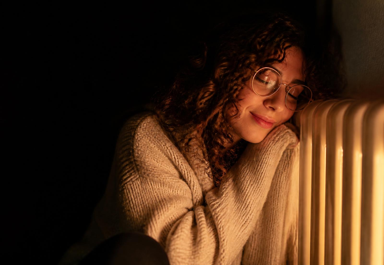 Vrouw leunt behaaglijk tegen een warme radiator